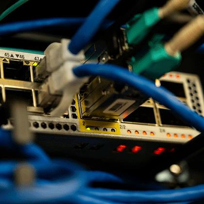 Nahaufnahme eines Netzwerk-Switches mit eingesteckten Ethernet-Kabeln.